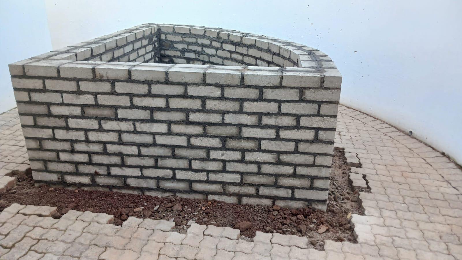 Brick planter construction within an existing paved area.