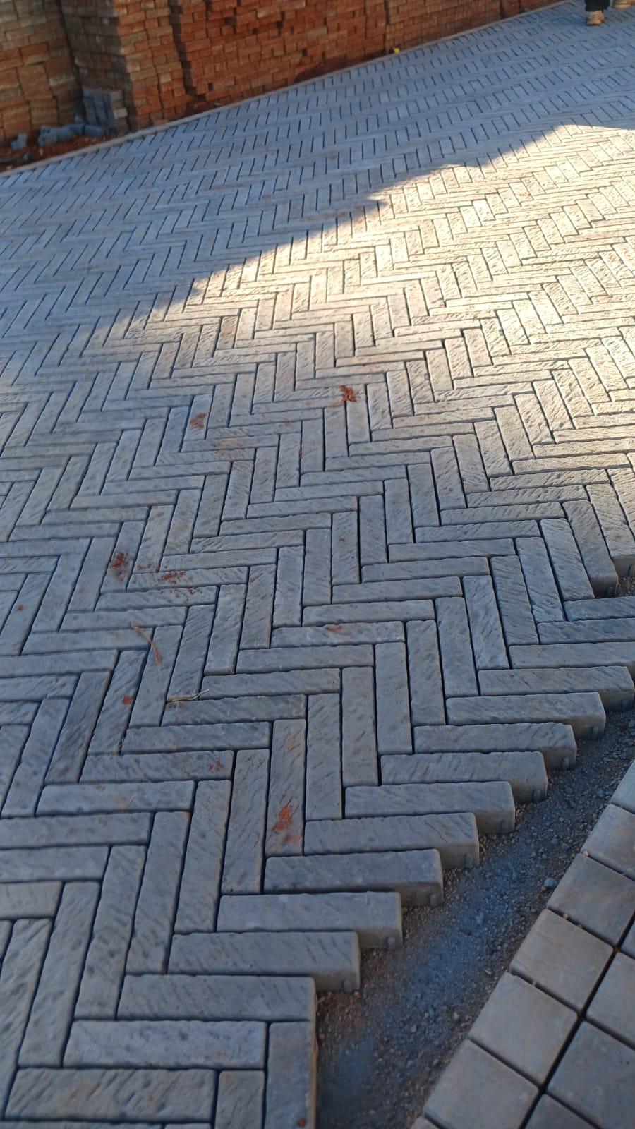 Grey interlocking pavers laid in a herringbone pattern with defined edges.